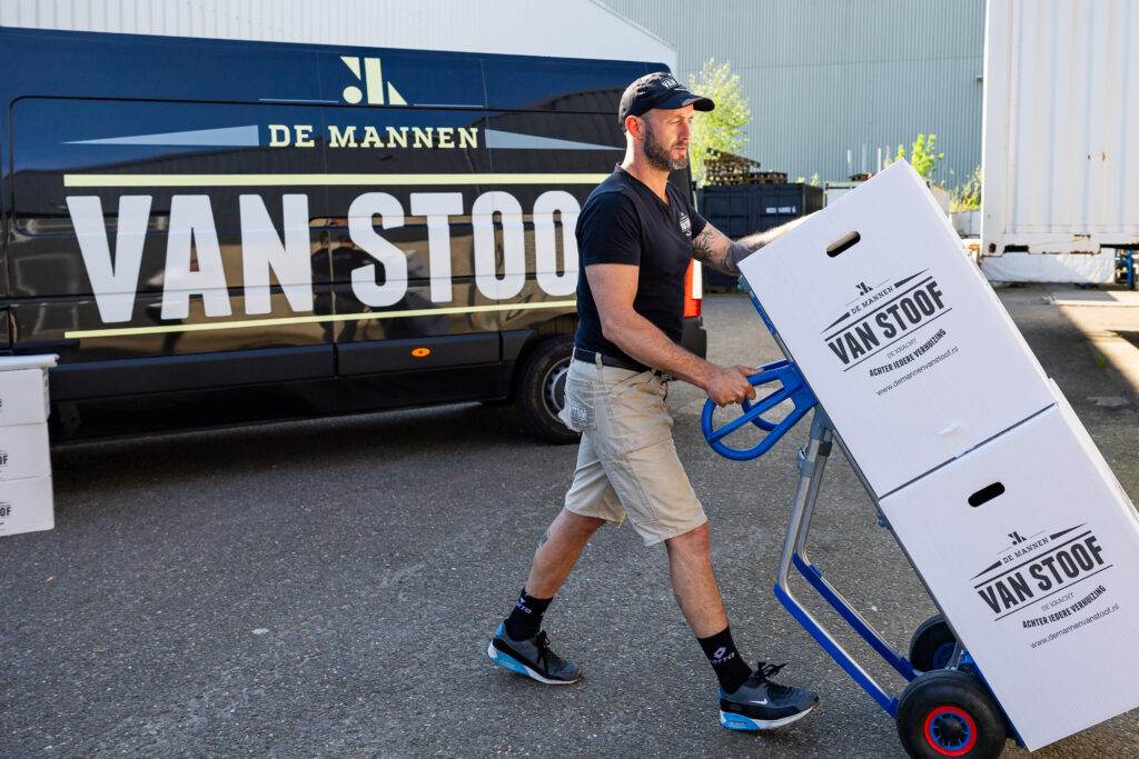 Verhuizer van De Mannen van Stoof rijdt verhuisdozen op een steekwagen naar de verhuiswagen