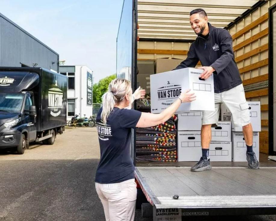 Lachende verhuizers van verhuisbedrijf Breda laden vrachtauto uit